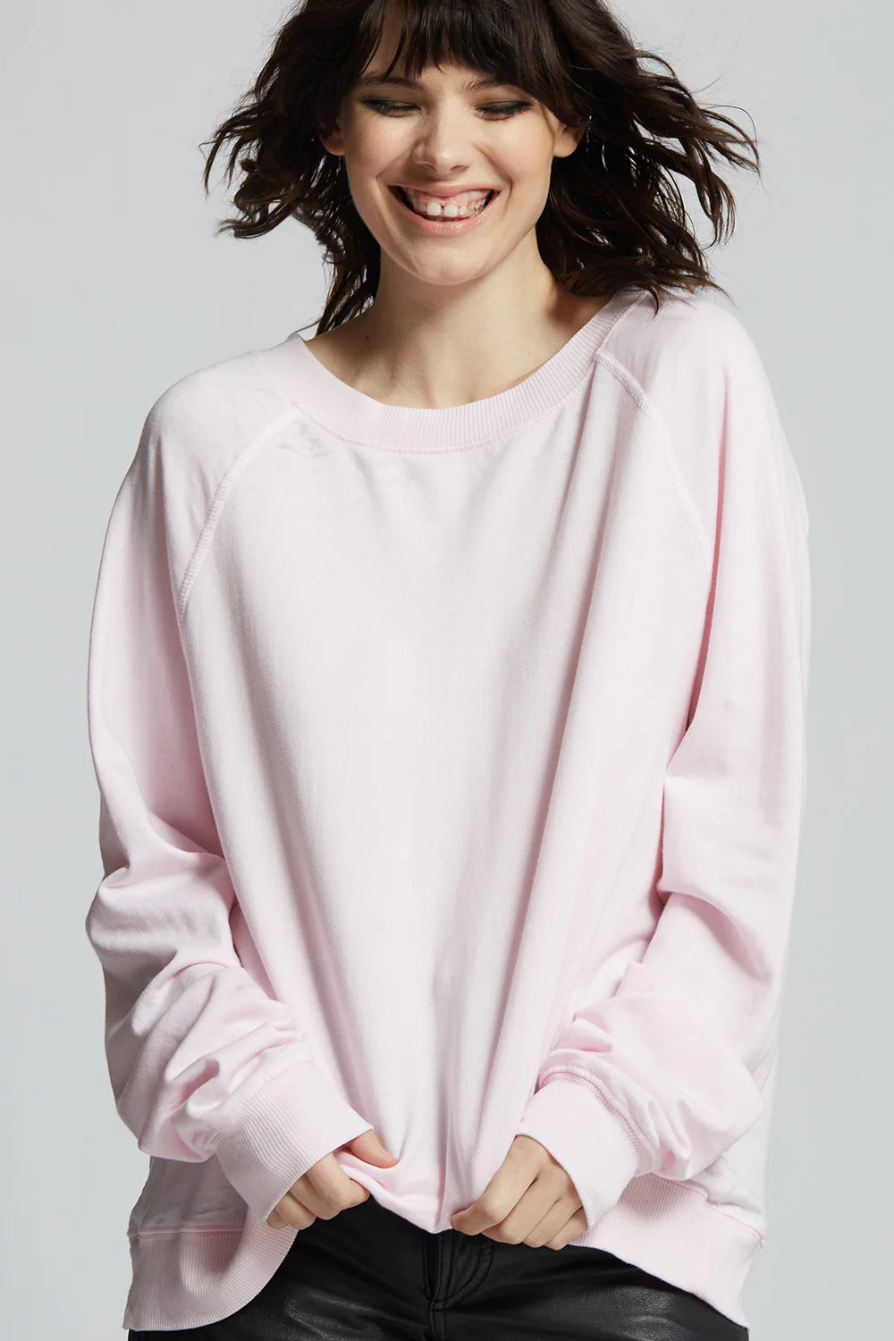 Woman wearing a light pink oversized sweater on a white background