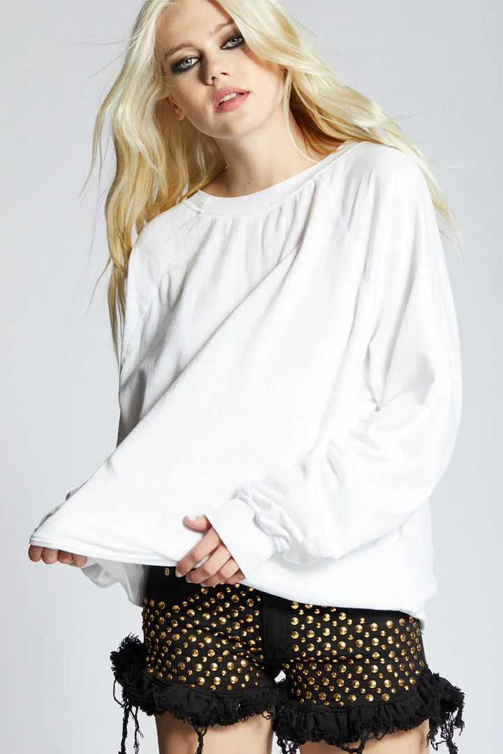 Woman wearing a white top and black shorts with gold accents on a plain background