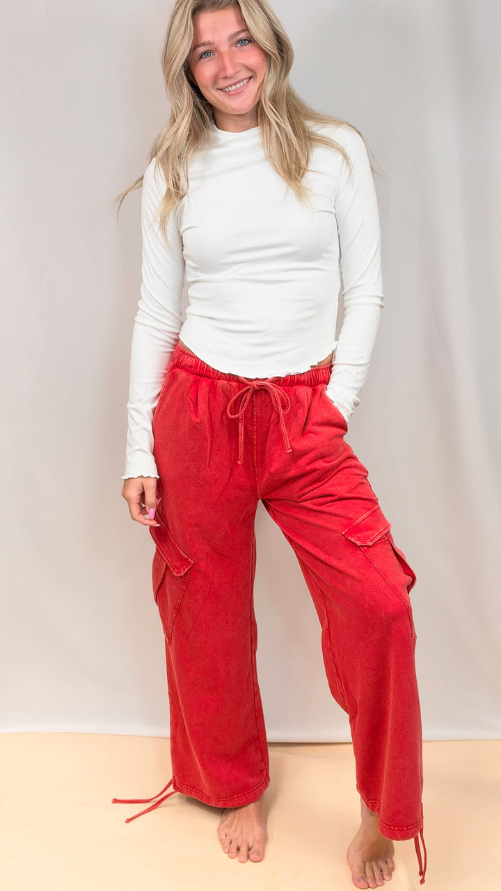 Woman wearing white top and red pants on plain background