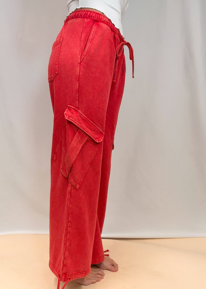 Woman shown from side view wearing red pants on plain background
