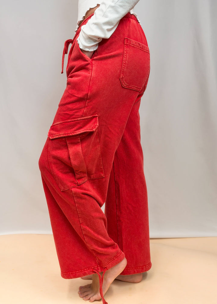 Woman shown from side view wearing red pants on plain background