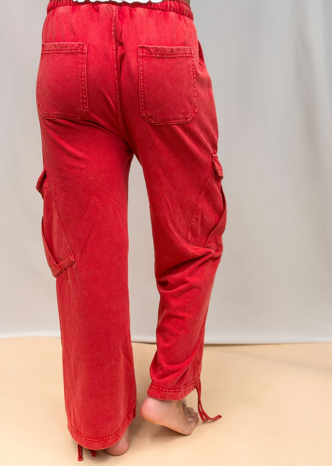 Woman shown from back wearing red pants on plain background
