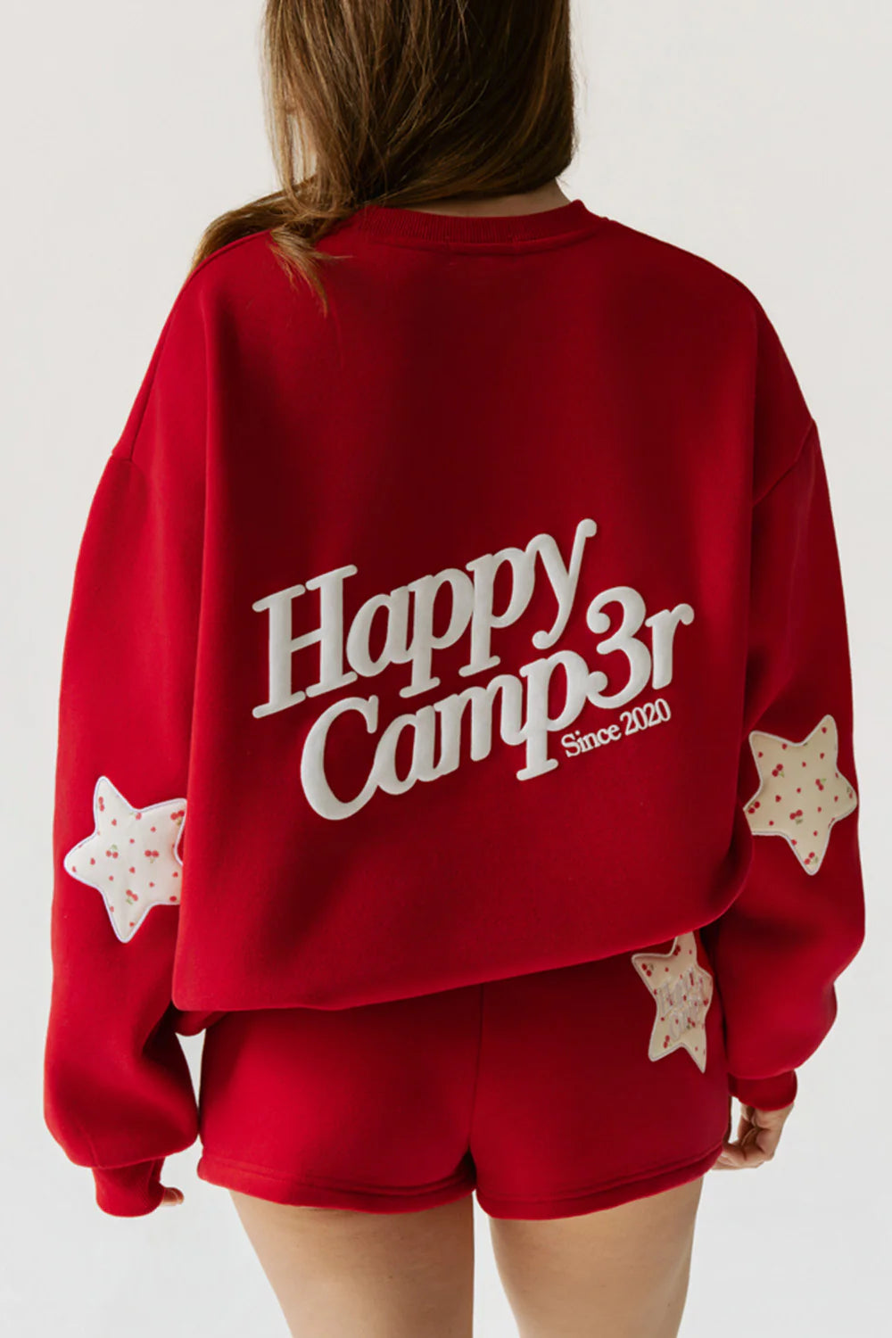 Red sweatshirt with 'Happy Camper Since 2021' text and star designs on a plain background