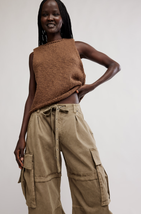 Woman wearing khaki barrel cargo pants and brown knit tank on white background