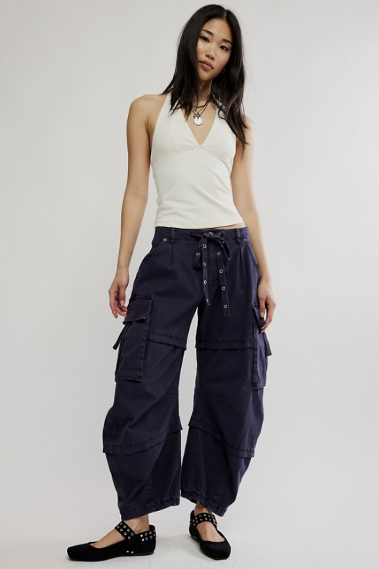 Woman wearing black cargo pants with white tank top on white background