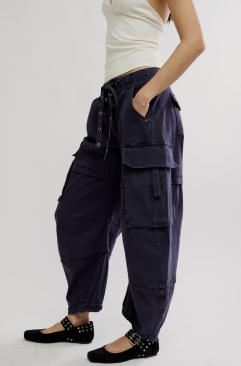 Woman wearing black cargo pants with white tank top on white background