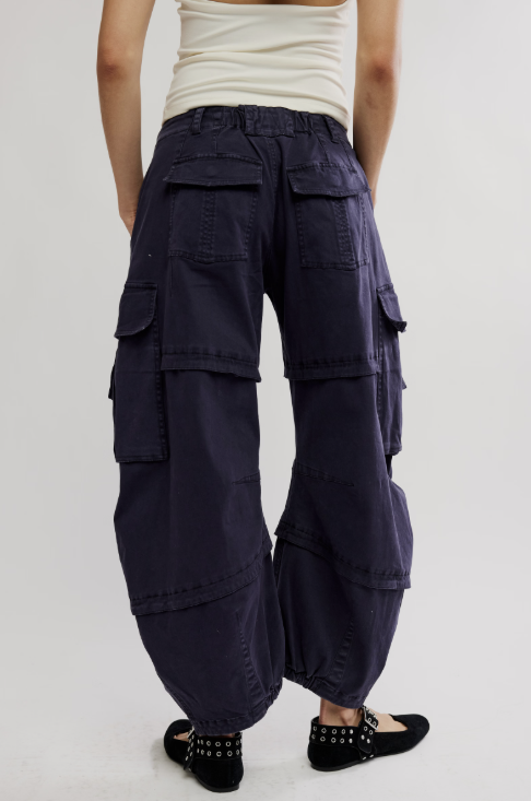 Back of woman wearing black cargo pants and white tank top on white background