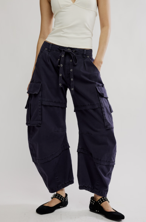 Woman wearing black cargo pants and white tank top on white background