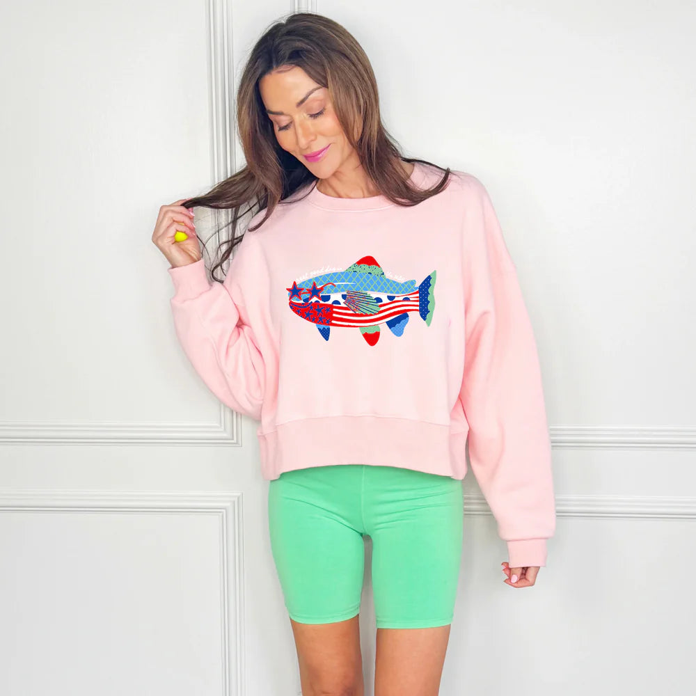 Woman wearing pink sweatshirt with patriotic fish graphic on white background