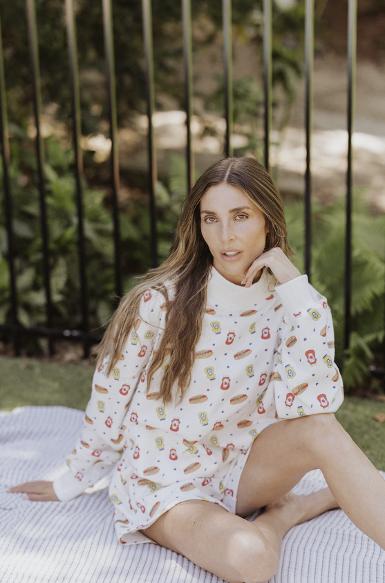 Woman sitting on a blanket outdoors wearing a patterned outfit.