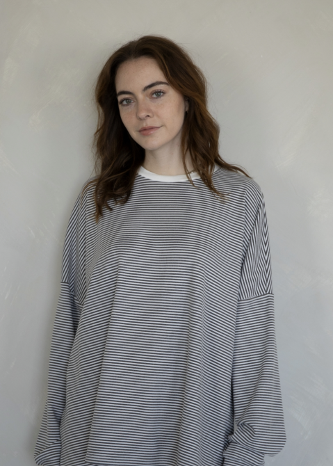 Woman wearing charcoal and white stripe top on plain background
