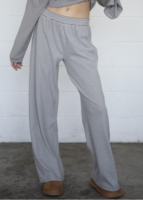 Woman wearing grey and white stripe bottoms and top with plain background