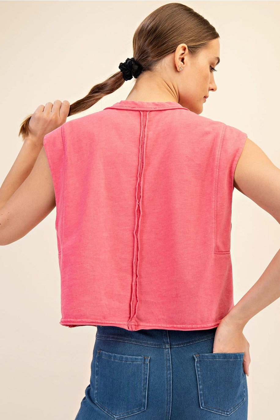 Woman wearing a pink sleeveless top with a beige background