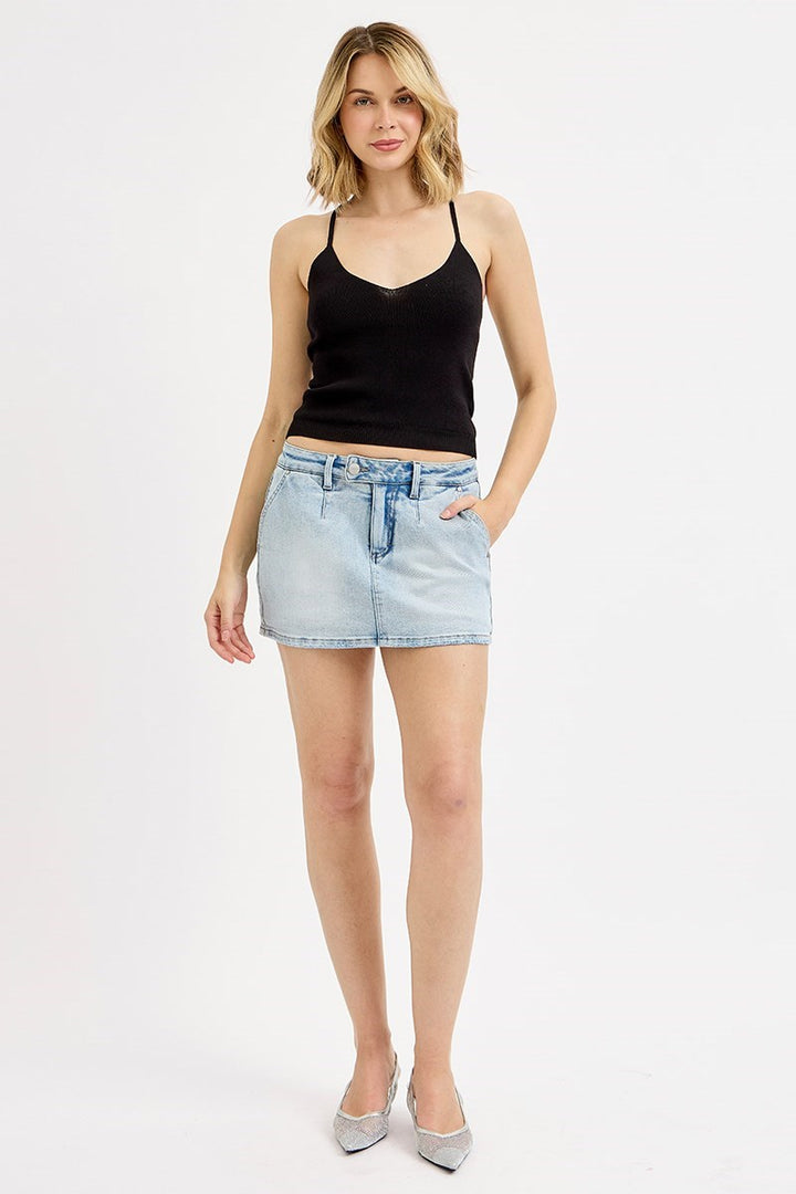 Woman wearing a black tank top and light blue denim shorts on a white background
