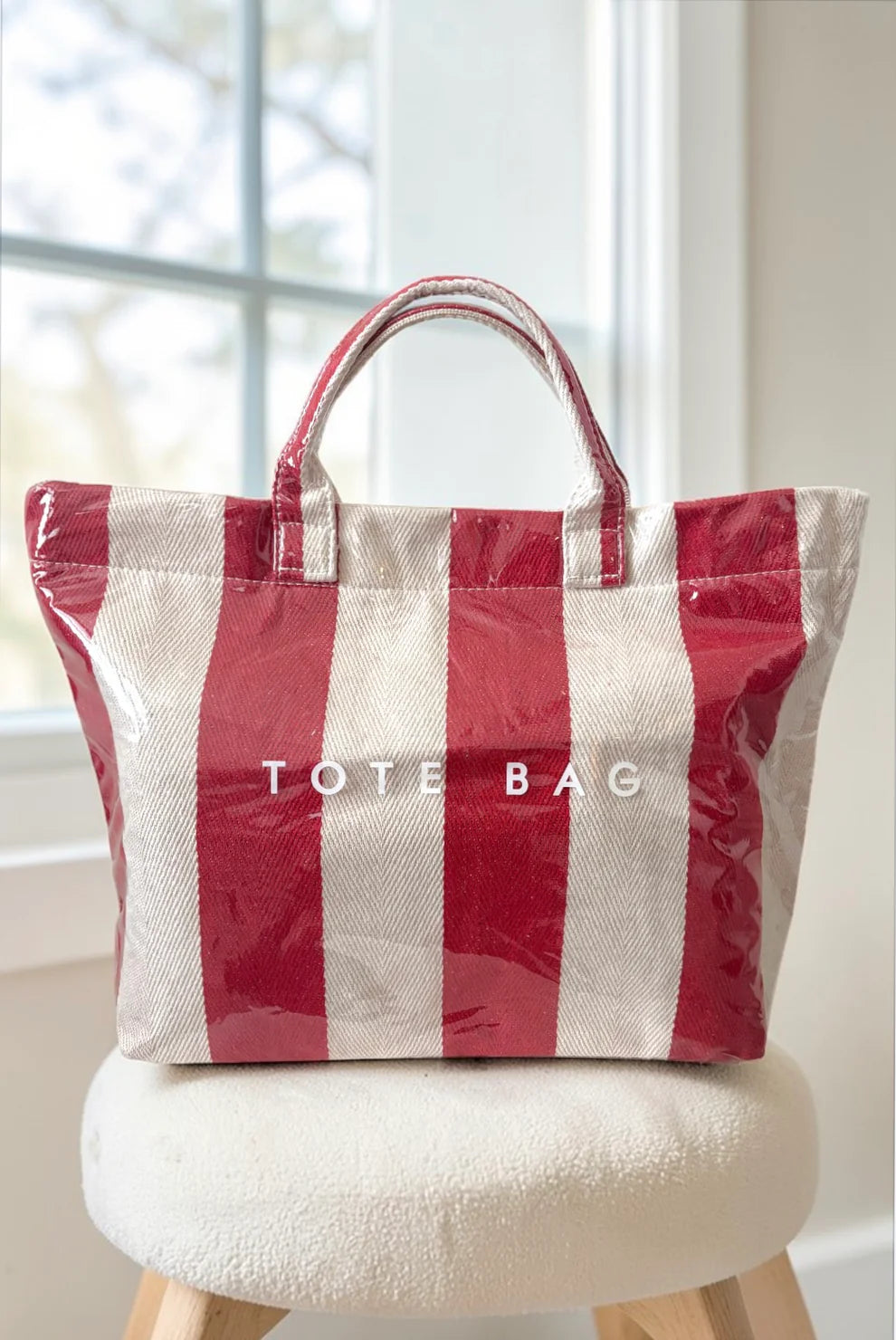 Red and white striped tote bag on a chair with a blurred window background