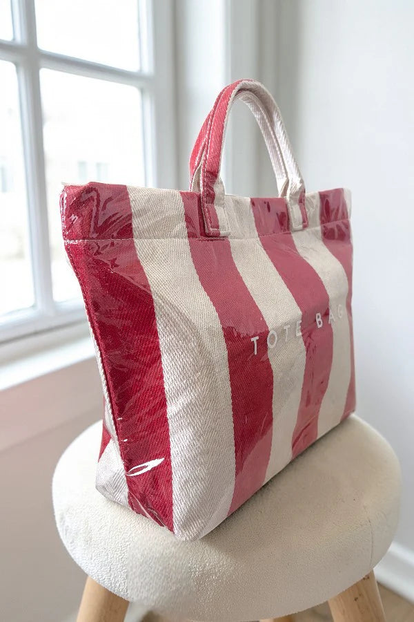 Red and white striped tote bag on a small stool by a window