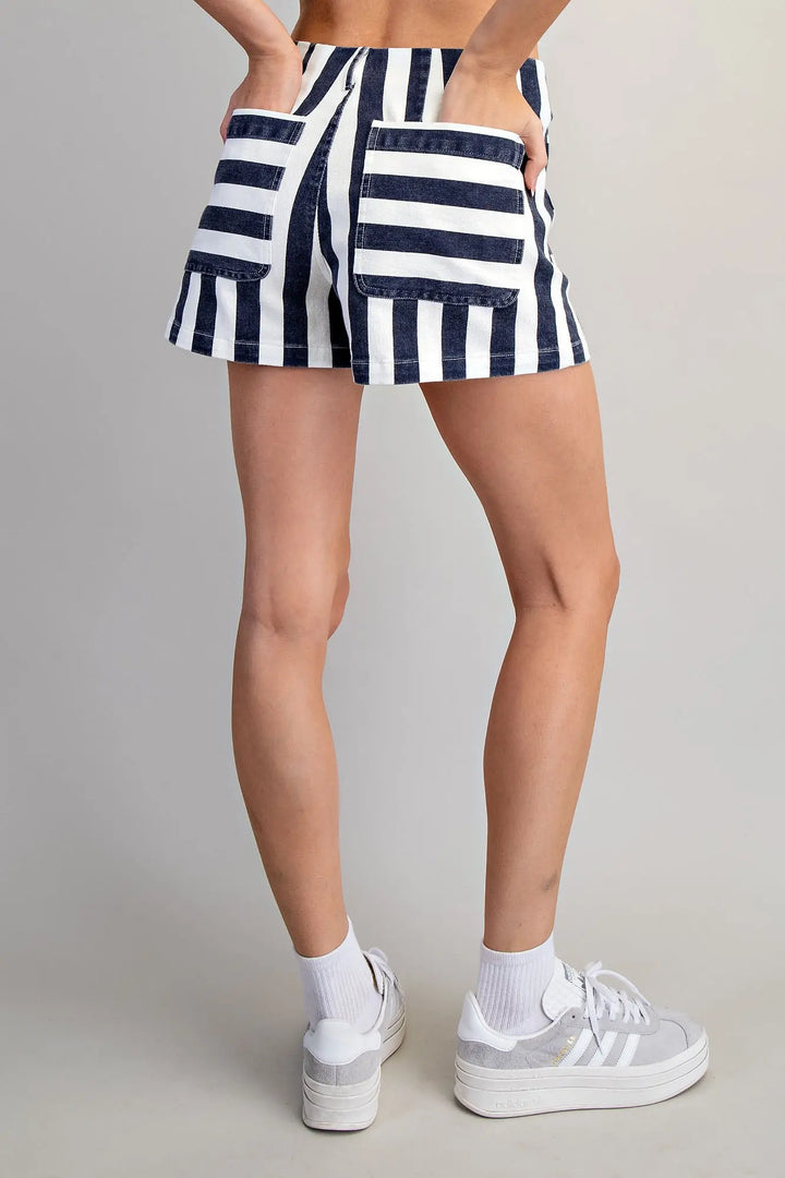 Person wearing a navy and white striped skirt with white sneakers on a plain background