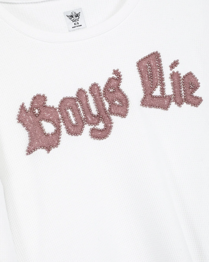 Close-up of a white ribbed knit top featuring the phrase &