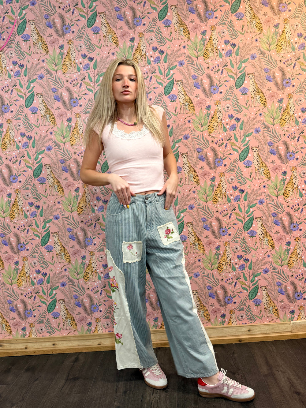 Woman standing in front of a decorative wall with floral and animal pattern