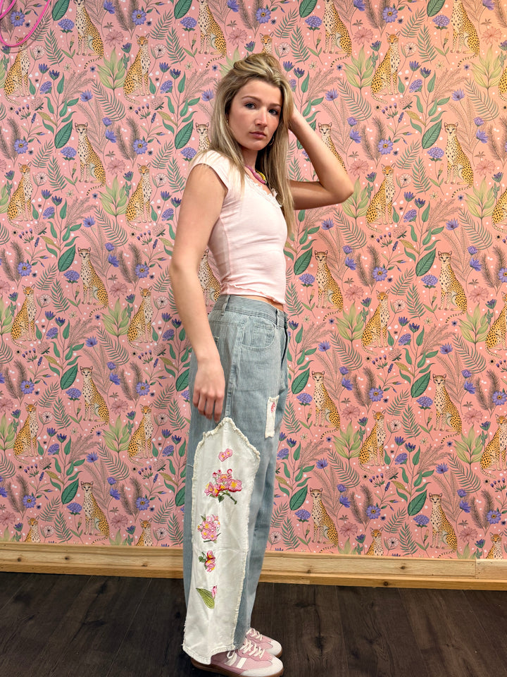 Woman standing against a pink floral wallpapered wall