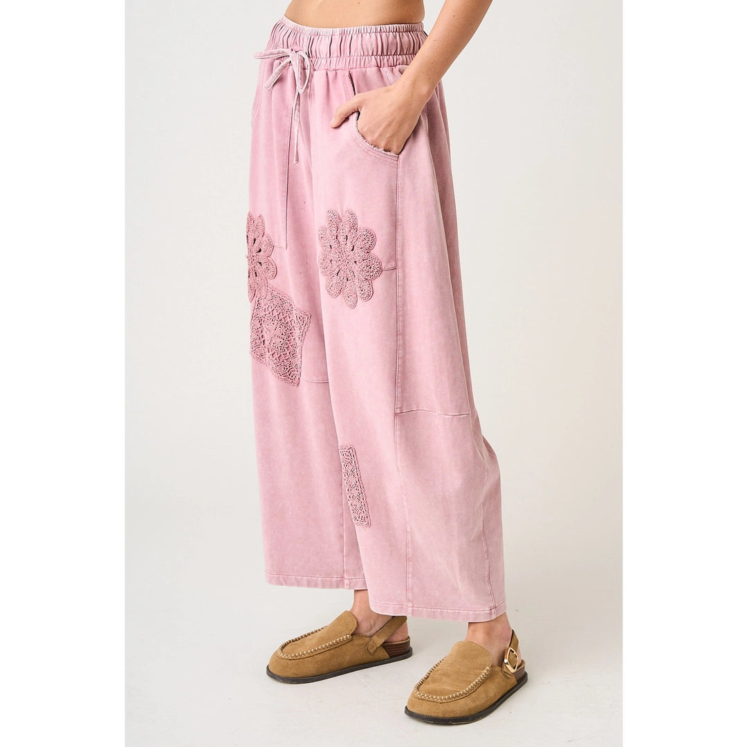 Pink pants with floral embroidery worn by a person on a white background