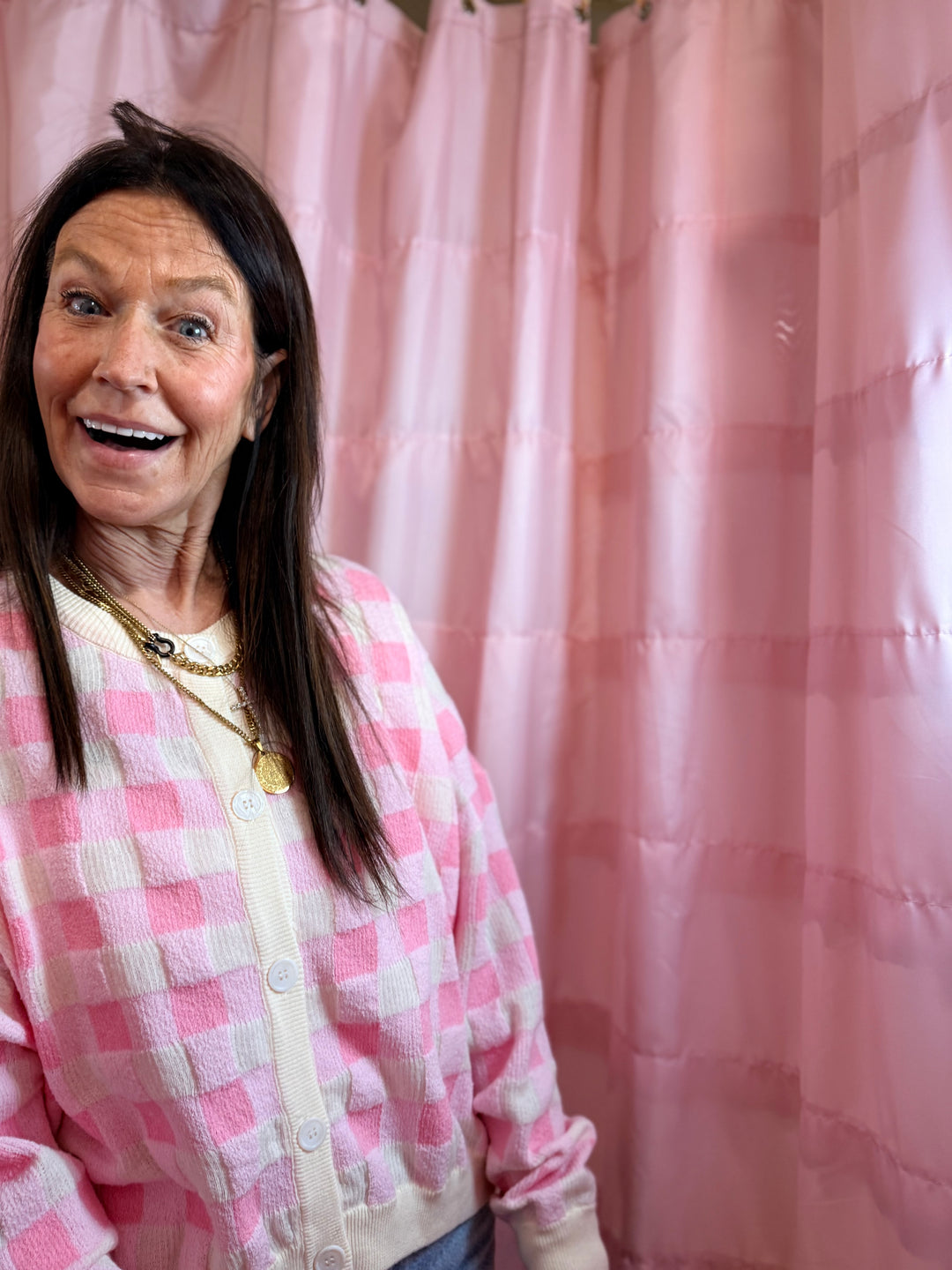 Person wearing a pink checkered outfit in front of a pink curtain
