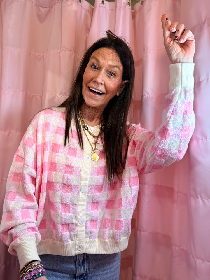 Woman wearing a pink and white checkered shirt in front of pink curtains