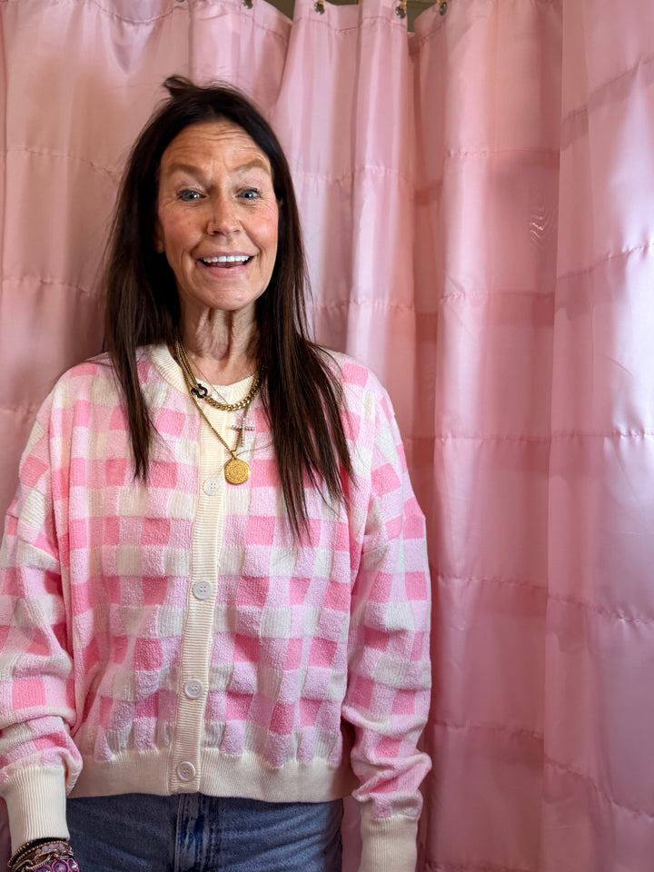 Person wearing a pink and white checkered jacket in front of a pink curtain