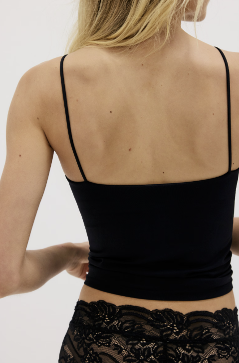 Black lace top worn by a person on a plain background