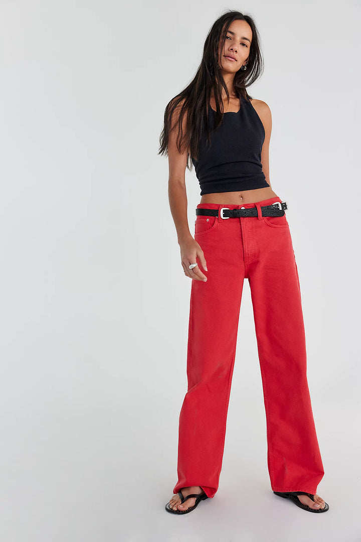 Woman wearing a black top and red pants on a white background