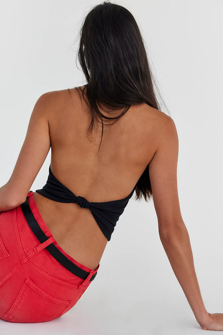 Person wearing a black top and red pants with a white background