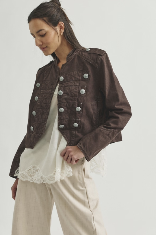 Woman wearing chocolate brown band jacket with beige tank and beige pants on white background