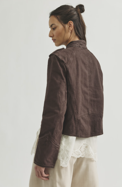 Woman shown from back wearing chocolate band jacket with beige pants on white background