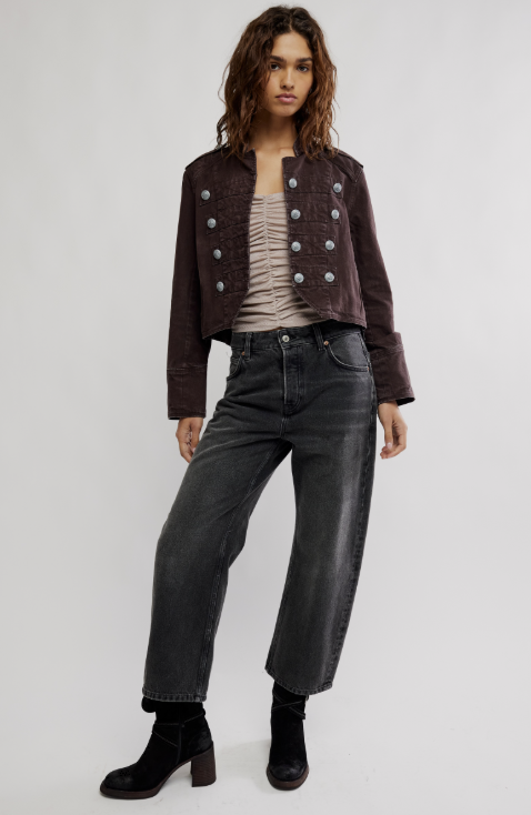 Woman wearing chocolate brown band jacket with beige tank and black barrel jeans on white background