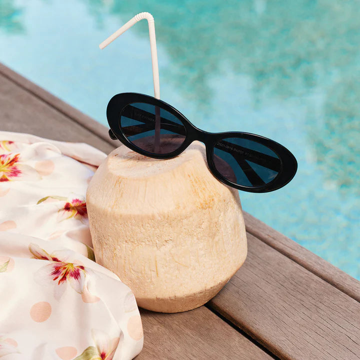 Black sunglasses sitting on coconut by pool