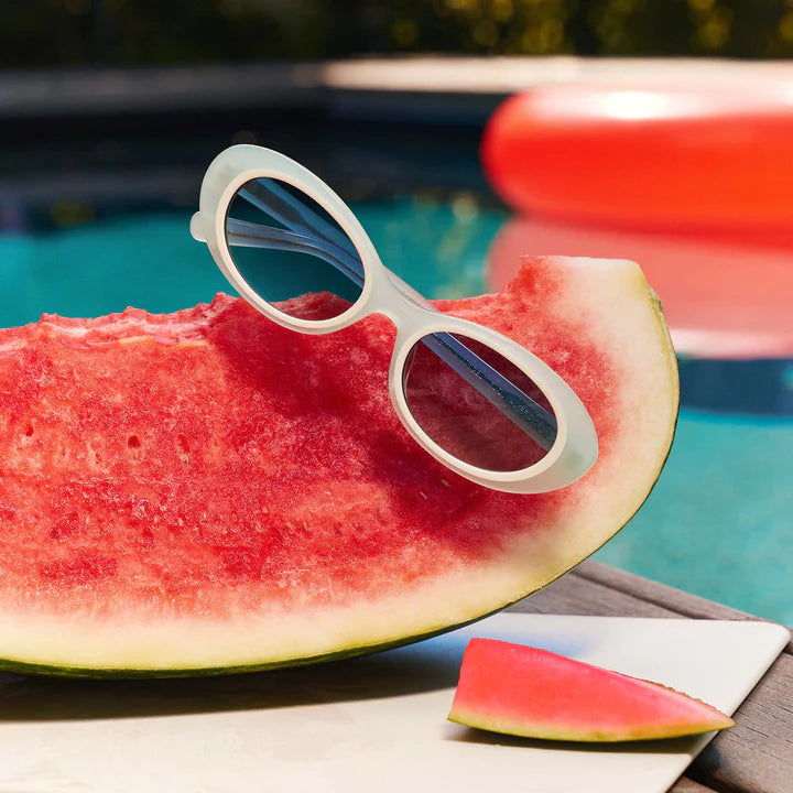 Sage green sunglasses sitting on a watermelon