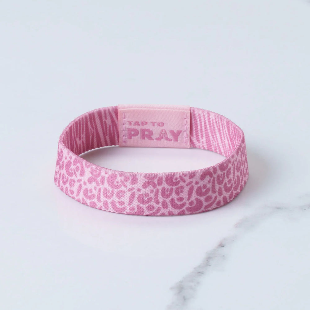 Pink wristband with 'Tap to Pray' text on a light gray background