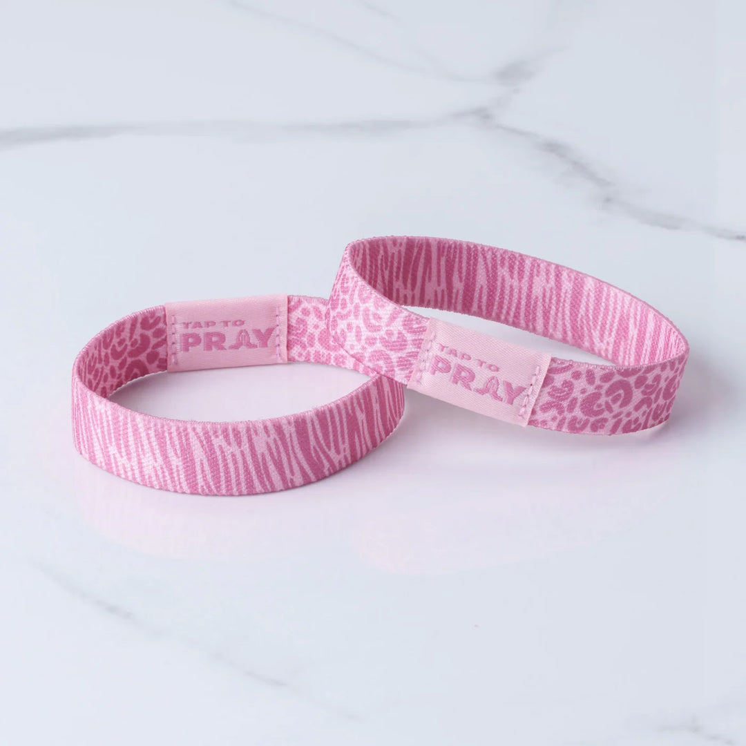 Two pink wristbands with patterns and text on a light gray background