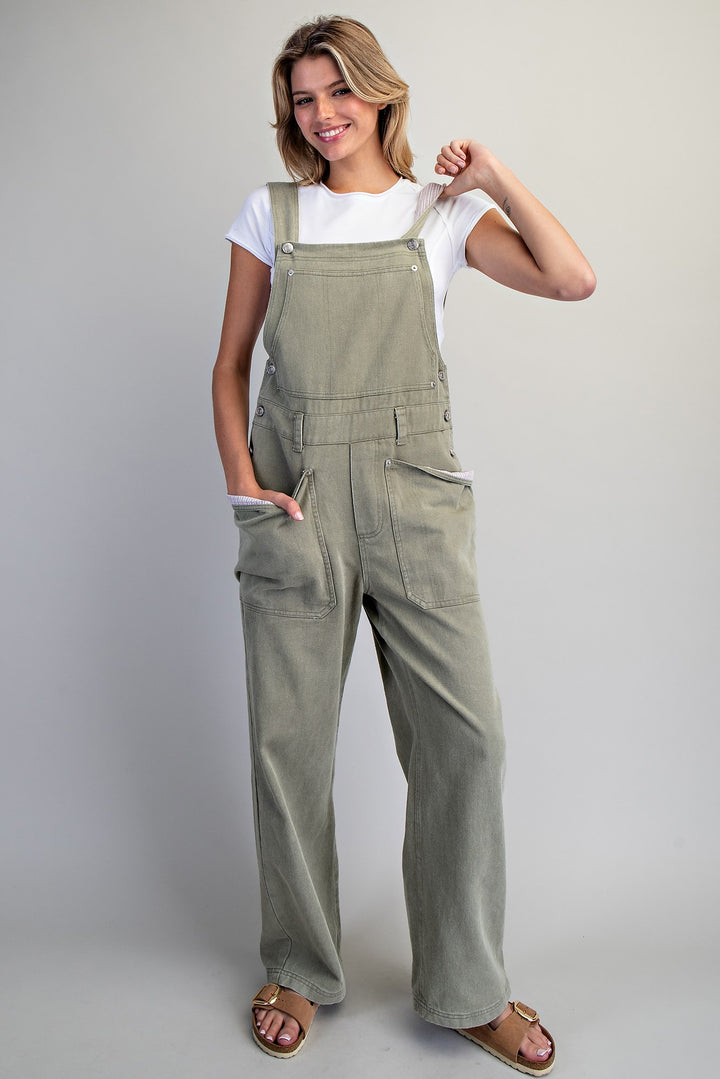Woman wearing green overalls against a plain background