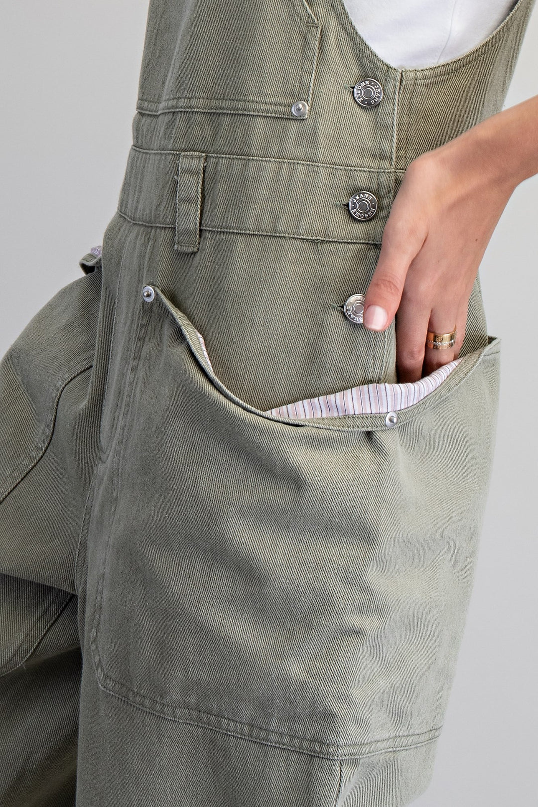 Woman wearing green overalls on plain background
