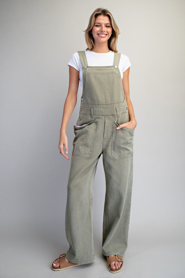Woman wearing green overalls against a plain background