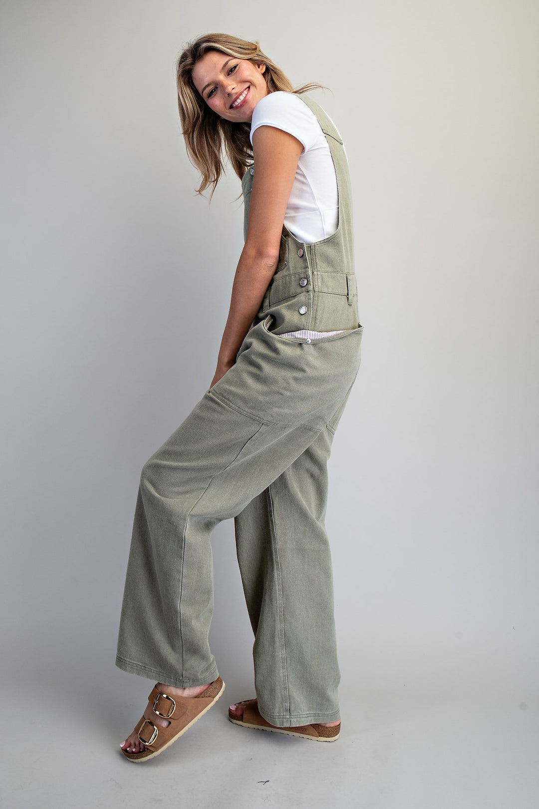 Woman wearing green overalls on a plain background