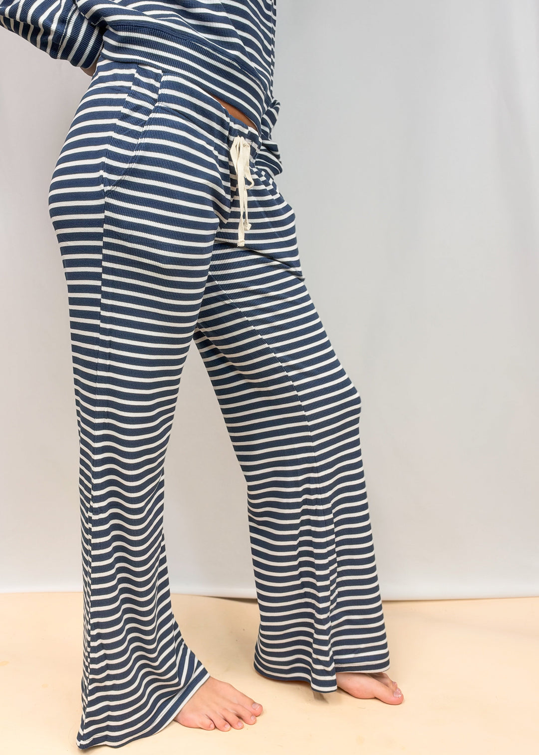 woman shown from waist down wearing navy and white stripe matching set on plain background