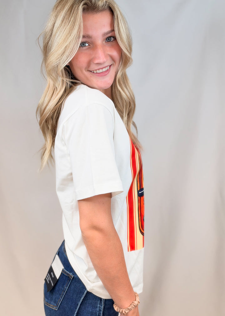 Woman wearing white graphic tee with jeans on plain background