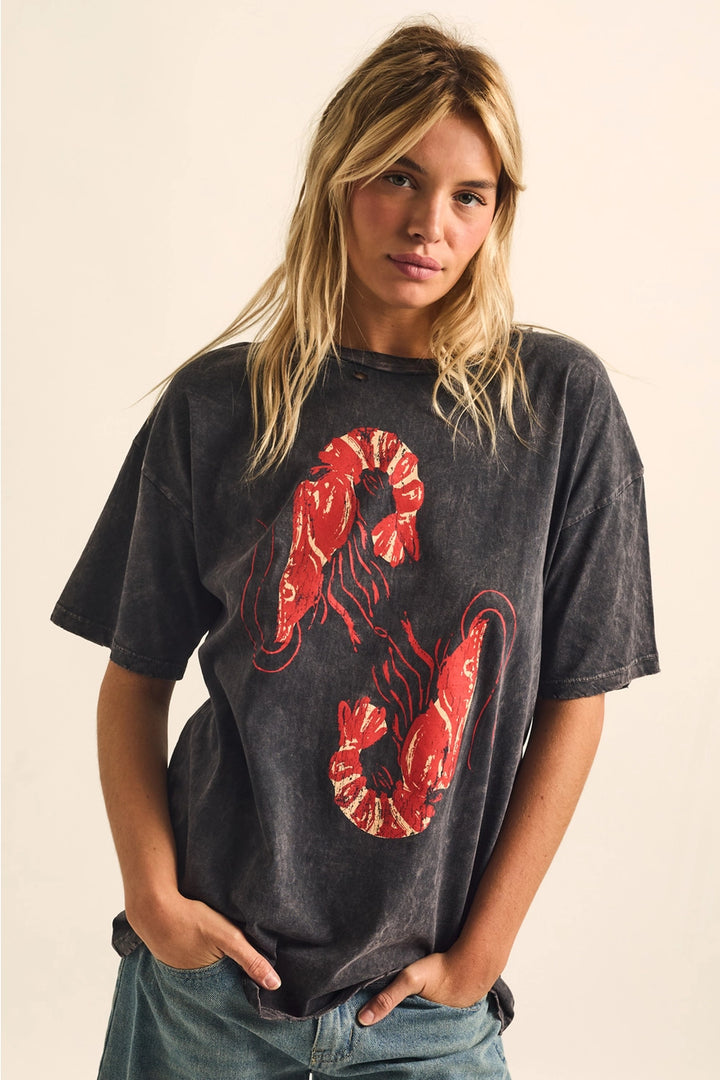 Woman wearing a black t-shirt with a red shrimp graphic on a beige background