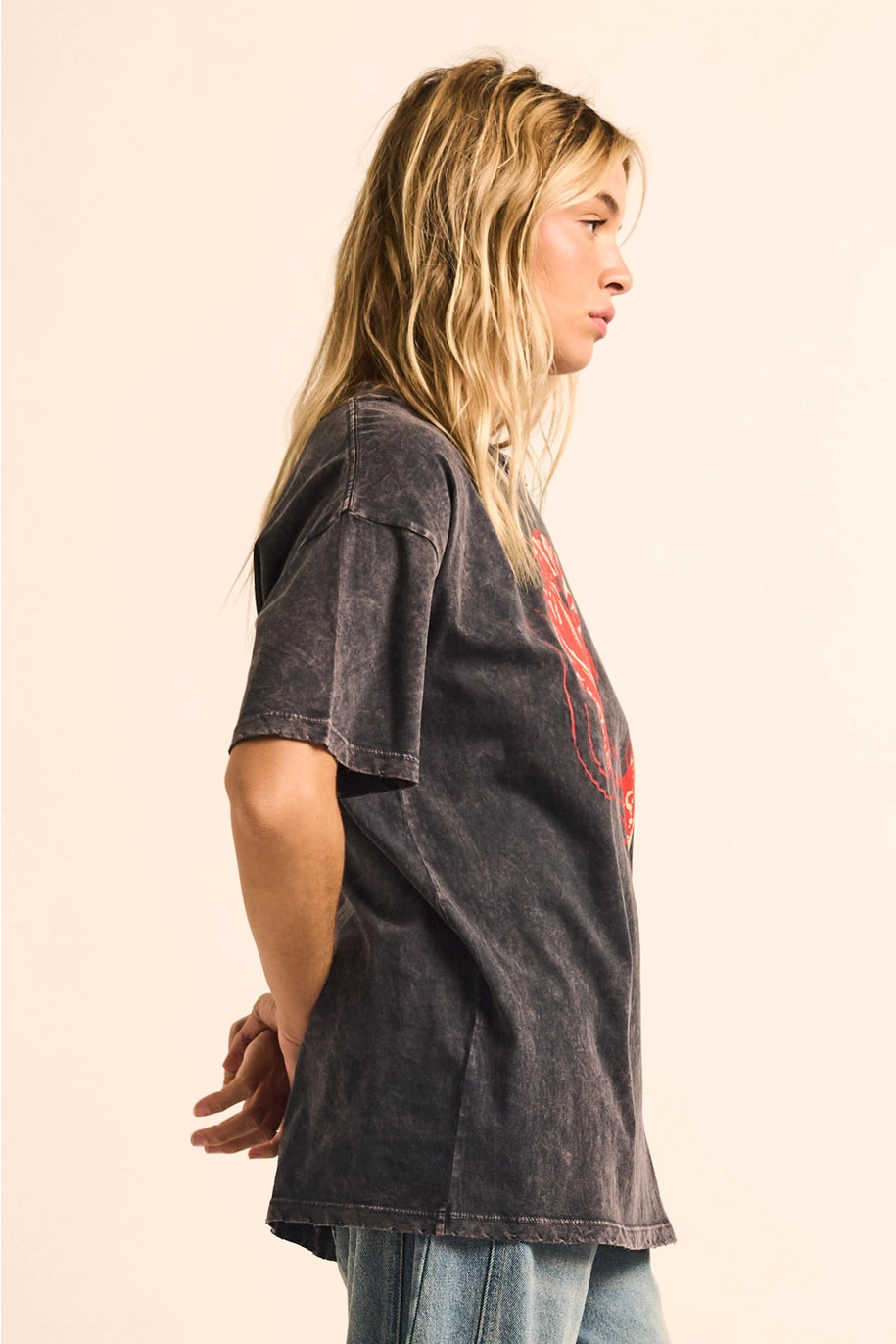 Person wearing a dark t-shirt with a graphic design on a beige background