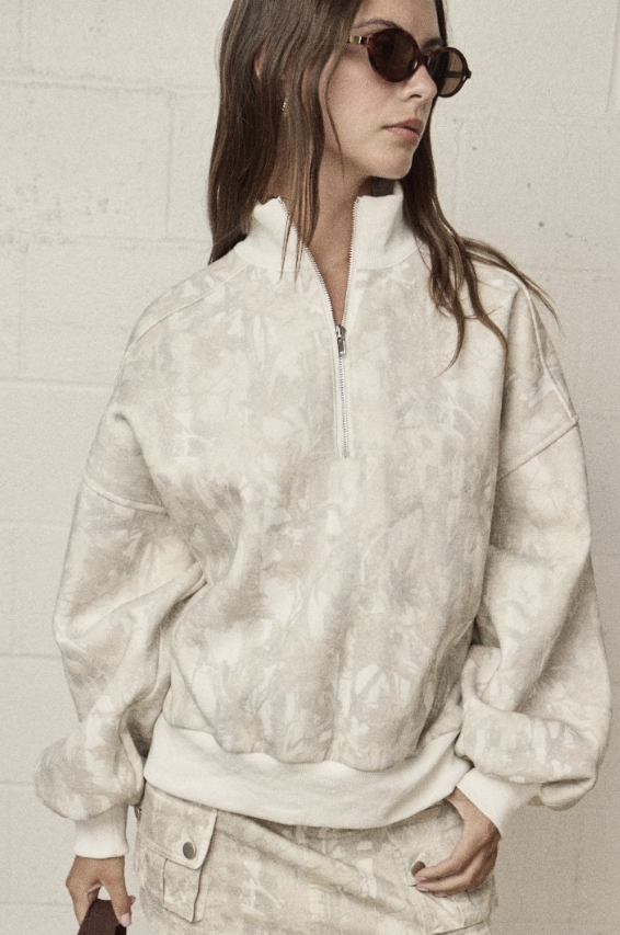 Woman wearing camo quarter zip on plain background