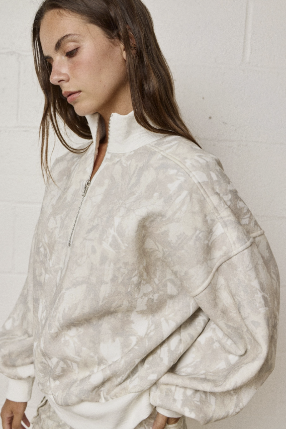 Woman wearing a white patterned jacket against a plain background