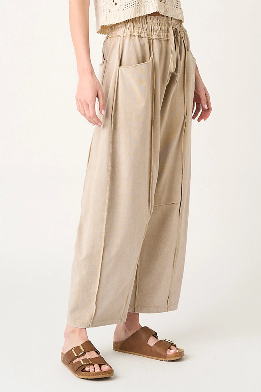 Person wearing beige wide-leg pants on a white background