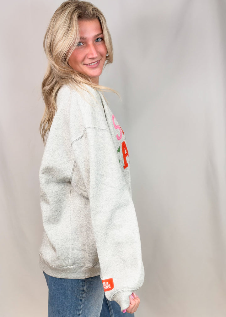 Woman shown from side view wearing grey sweatshirt and jeans on plain background